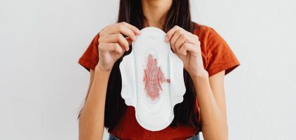 Young woman holding a sanitary pad demonstrating menstrual health awareness indoors.