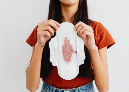 Young woman holding a sanitary pad demonstrating menstrual health awareness indoors.