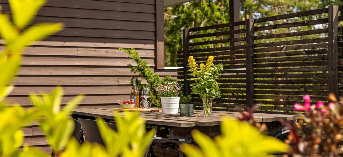 Outdoor patio with wooden table, chairs, and vibrant plants in summer.