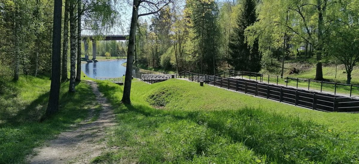 Idyllic spring landscape with a path through lush greenery by a calm river.