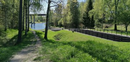 Idyllic spring landscape with a path through lush greenery by a calm river.